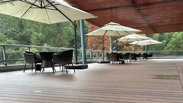 El decking al aire libre de WPC tiene mesas, sillas y sombrillas