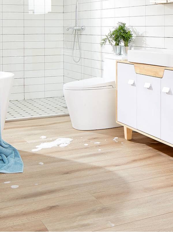 A boy is washing the dog in the bathtub covered with LVT flooring.