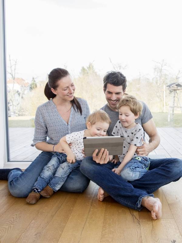 Four family members are sitting on the SPC flooring and watching iPad.