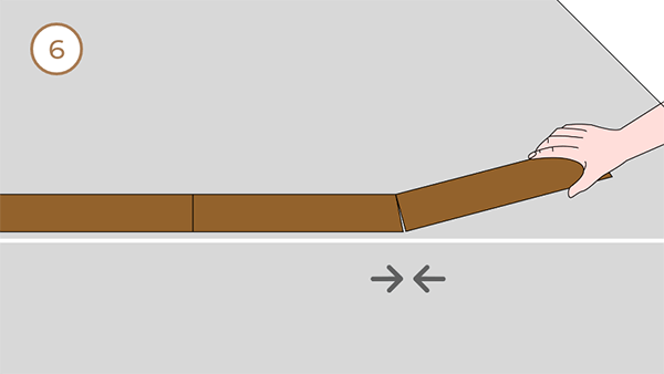 A hand laying the flooring one by one.