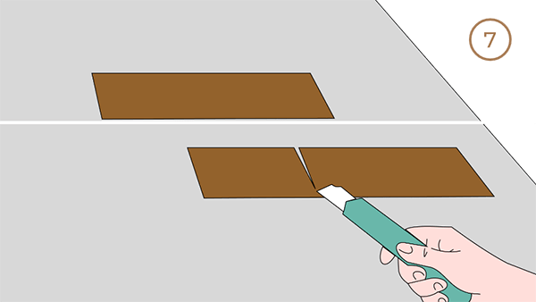 A hand cutting a piece of flooring.