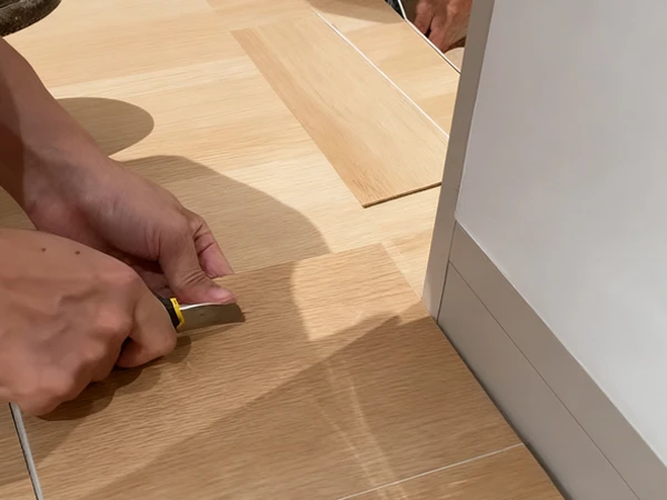 Workers are using tools to cut SPC flooring.