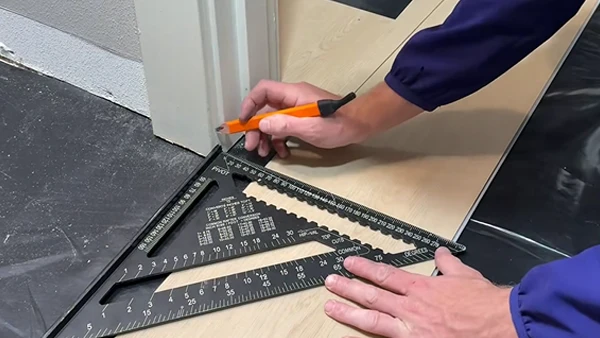 Los trabajadores están utilizando herramientas para marcar y cortar pisos SPC