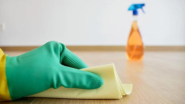 Un hombre con guantes de goma limpia el suelo SPC con una toalla