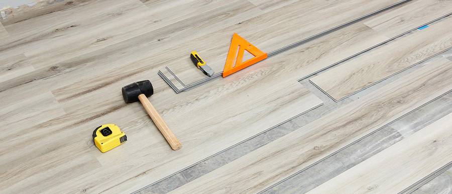 A man is installing SPC flooring with necessary tools.