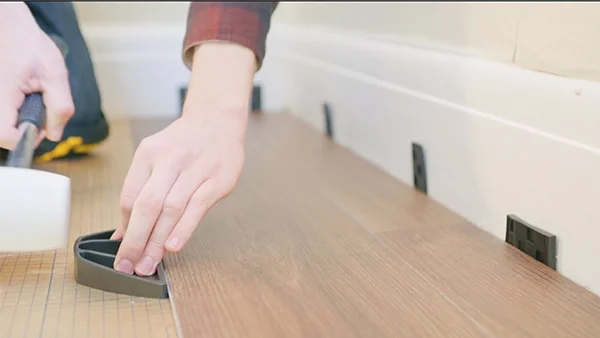 Los trabajadores están instalando pisos de clic SPC en el piso de baldosas de cerámica.