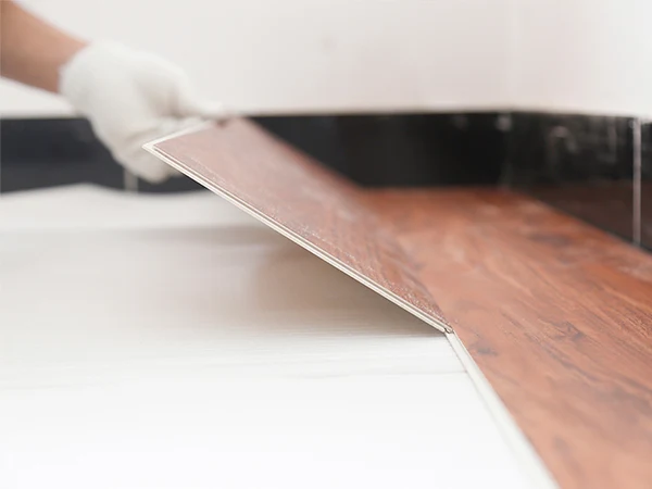 Workers are interlocking and installing SPC flooring on a flat base layer.