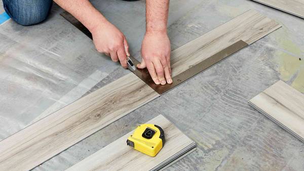 A worker is installing vinyl flooring.