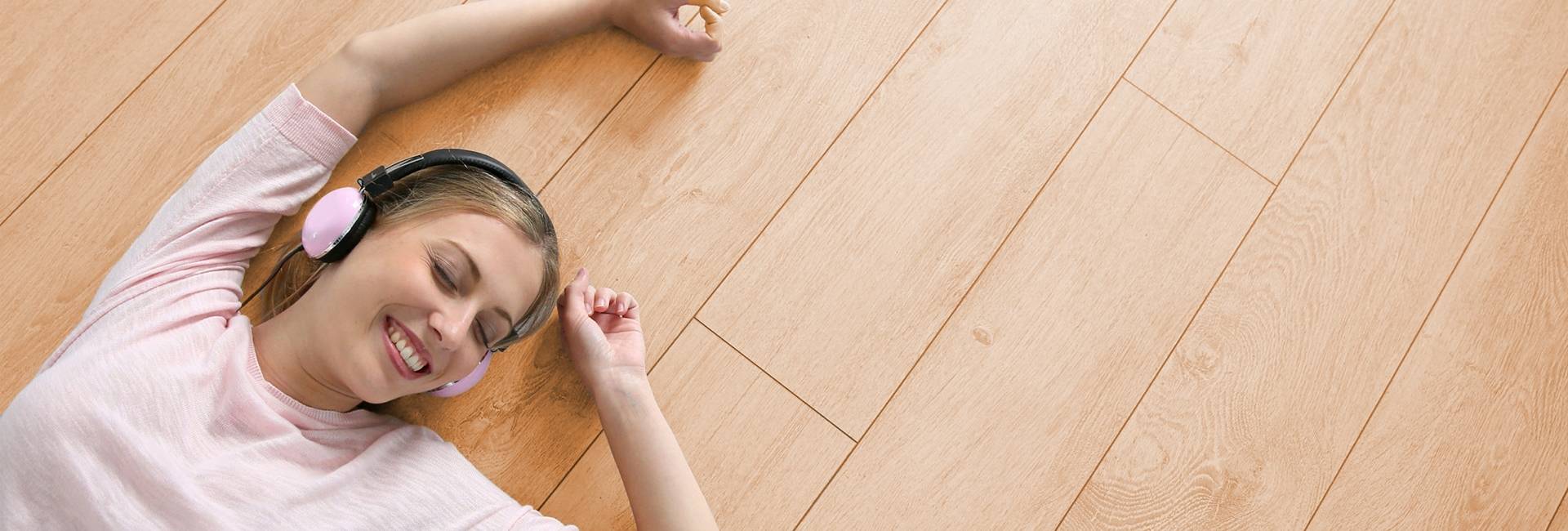 A young girl is laying on the wood look SPC flooring and smiling.