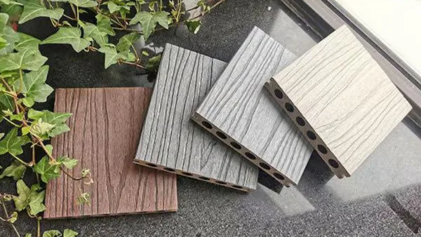 El suelo de WPC de 4 colores diferentes se coloca al lado de las plantas verdes.